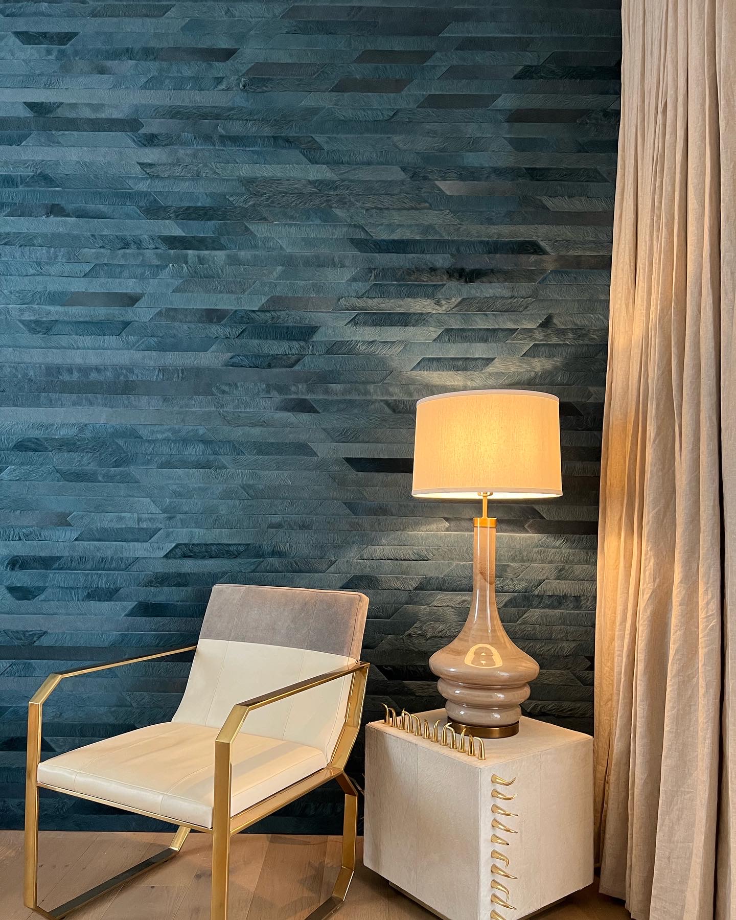 Textured feature wall with brass and leather chair